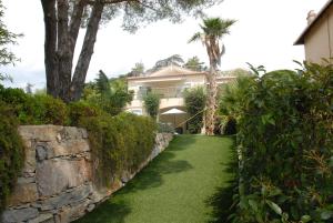 a house with a stone wall and a green lawn at Sainte Maxime 3 pièces in Sainte-Maxime