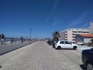 a street with cars parked on a sidewalk next to the beach at Apartament Pedro&Pérolla in Gafanha da Vagueira