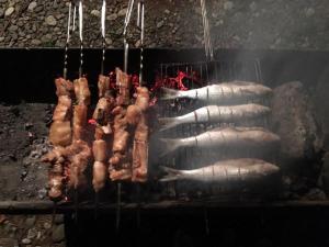 a bunch of meat cooking on a grill at Kety House in Makhinjauri