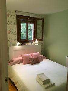1 dormitorio con 1 cama con sábanas blancas y almohadas rosas en Lunas de Siguenza, en Sigüenza
