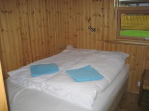 a white bed with two blue pillows on it at Vestri Pétursey in Vestri Pétursey