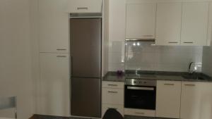 kuchnia z białymi szafkami i lodówką ze stali nierdzewnej w obiekcie Apartamento Gallego VUT-PO-02510 w mieście Sanxenxo