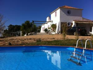 Monte da Casa Branca by Hi Alentejo في São Bartolomeu da Serra: مسبح ازرق امام بيت ابيض