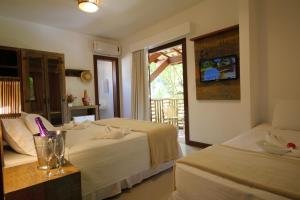 a hotel room with two beds and a window at Pousada João Sol in Praia do Forte