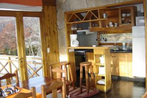 eine Küche mit Holzschränken sowie einem Tisch und Stühlen in der Unterkunft Casa de Piedra in San Martín de los Andes