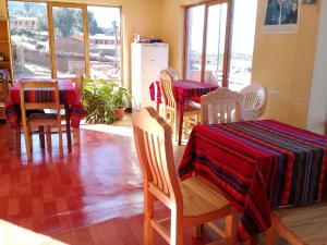 een eetkamer met 2 tafels en stoelen met rode en zwarte tafelkleden bij Hostal Tawri in Isla de Sol