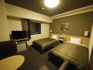 a hotel room with two beds and a flat screen tv at Hotel Route Inn Hashimoto in Hashimoto