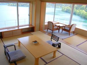 een kamer met een tafel, stoelen en ramen bij Shikaribetsu Kohan Onsen Hotel Fusui in Shikaoi