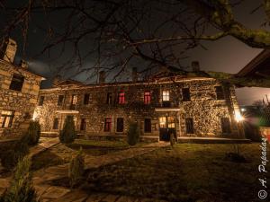 uma antiga casa de pedra com janelas vermelhas à noite em Al Monte Hotel em Vronterón