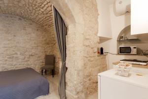 een slaapkamer met een bed en een stenen muur bij Dammuso delle Gioie in Scicli