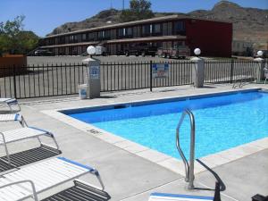 a swimming pool with two chairs and a building at Western Ridge Motel in Wendover