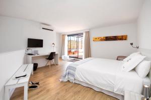 a white bedroom with a white bed and a desk at Horta d'en Rahola - Adults Only in Cadaqués