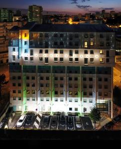 a building with cars parked in a parking lot at Hotel Reseda in Bagnolet