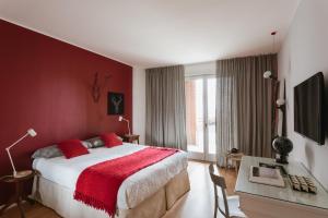 ミラノにあるVivere Milano Isolaの赤い壁のベッドルーム1室、ベッド1台、デスクが備わります。