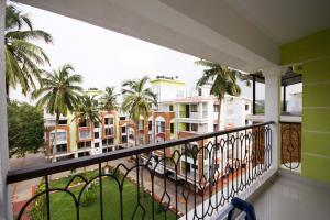 a balcony with a view of palm trees and buildings at Monarch Palms- Serviced Apartments (Managed by HNH Homes) in Candolim