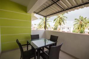 a table and chairs on a balcony with palm trees at Monarch Palms- Serviced Apartments (Managed by HNH Homes) in Candolim