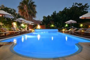 una piscina por la noche con sillas y sombrillas en Villa Katerina, en Parikia