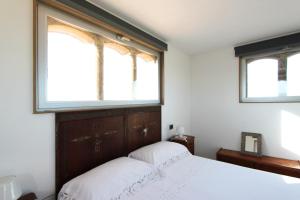 a bedroom with two windows and a bed with white sheets at Zahara in Carlentini