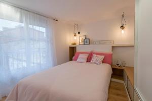 1 dormitorio con cama blanca y almohadas rosas en Apartamento Luscofusco, en Ourense