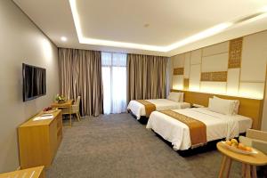 a hotel room with two beds and a desk at Patra Semarang Hotel & Convention in Semarang