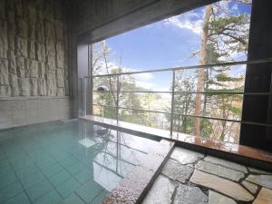 a room with a swimming pool with a large window at Route Inn Grantia Hidatakayama in Takayama
