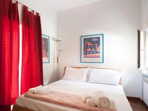 ボローニャにあるUR-NEST San Feliceのベッドルーム1室(赤いカーテン、ベッド1台、タオル付)