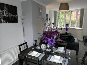 a dining room with a table with purple flowers on it at Whiteley Street in Manchester