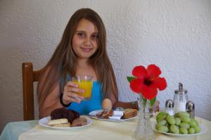 a woman sitting at a table with a glass of orange juice at Effie Hotel in Skala