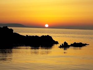 a sunset over the ocean with rocks in the water at Effie Hotel in Skala