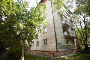 un viejo edificio de ladrillo con un árbol delante de él en 1kv Khar'kovskaia 69 (1), en Tyumen