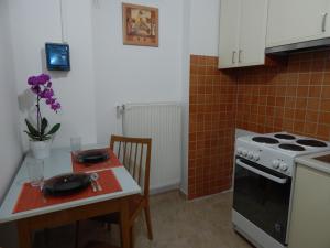 cocina con mesa, fogones y mesa con sillas en Csillagvirág Apartman, en Mosonmagyaróvár