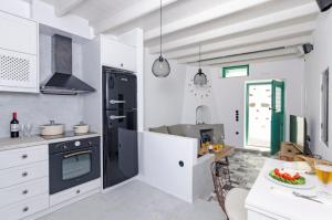 uma cozinha com armários brancos e um frigorífico preto em Tholos Deluxe House em Astypalaia