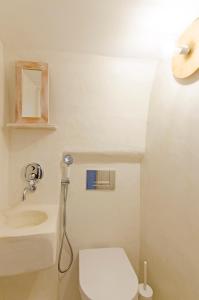 a white bathroom with a toilet and a sink at Tholos Deluxe House in Astypalaia Town