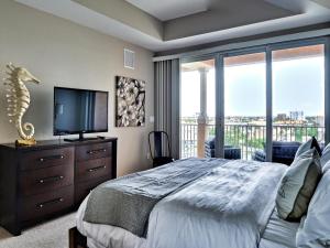 a bedroom with a bed with a television and a balcony at Harborview Grande 700 Waterfront Condo in Clearwater Beach +17 photos