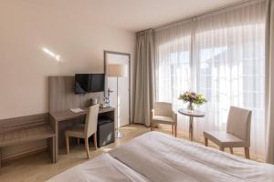 a hotel room with a bed and a desk and a window at Hôtel de la Rose in Fribourg