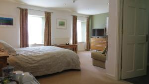 a bedroom with a bed and a couch and a television at The Boat House Bed and Breakfast in Laugharne