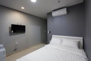 a bedroom with a white bed and a tv at O'guest in Haeundae in Busan