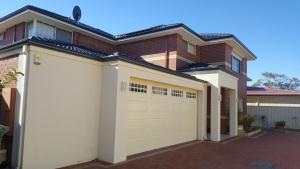 a house with a white garage door in front of it at Vimal's Homestay in Perth