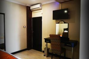 a hotel room with a desk and a television on the wall at Kismet Hotel in Pietermaritzburg