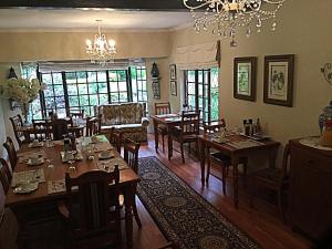 una sala da pranzo con tavoli, sedie e lampadario a braccio di Warrens Guest House a Hillcrest