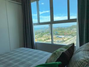 a bedroom with a bed and a large window at Baan Kiang Fah By Greenday in Hua Hin