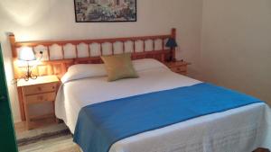 a bedroom with a white bed with a blue blanket at Can Xumeu Miquel in Sant Ferran de Ses Roques
