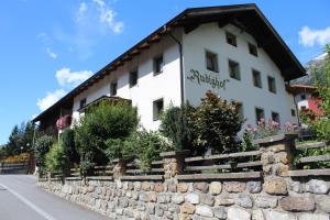 a building with a stone wall in front of it at Rudighof in Pettneu am Arlberg