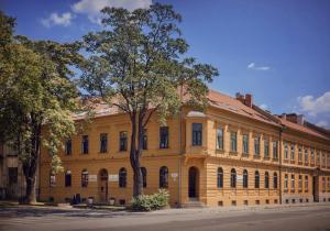 a large yellow building with trees in front of it at City Residence Apartment Hotel in Košice