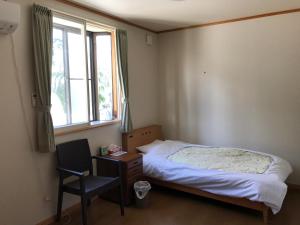 ein Schlafzimmer mit einem Bett, einem Stuhl und einem Fenster in der Unterkunft Kakunodate Guesthouse Fuga in Senboku