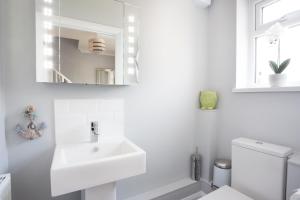 uma casa de banho branca com um lavatório e um espelho em Northwood 2 em Broadstairs