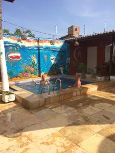 two children in a swimming pool with a mural at Pousada Villa Calango in Canoa Quebrada