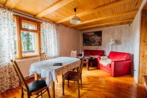 a living room with a table and a red couch at Domek pod bukami in Szymbark