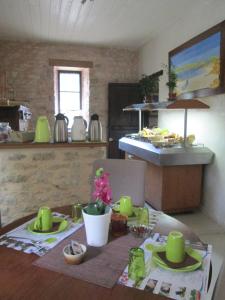 una cocina con una mesa con platos verdes. en Les Jardins d'Ungaro / Manoir La Barrière, en Le Vigan