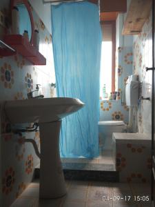 a bathroom with a sink and a blue shower curtain at Villa Spaia in Brancaleone Marina